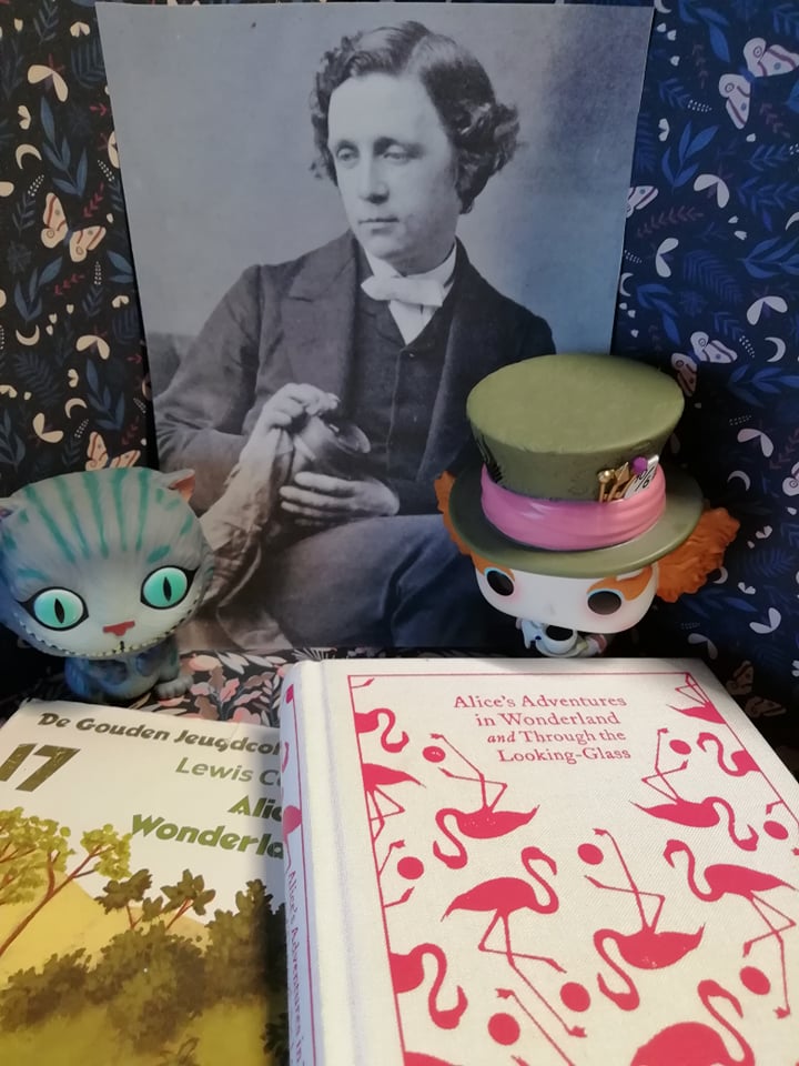 Lewis Carroll accompanied by Cheshire cat and Mad Hatter with my two copies of his work. -BookDragon